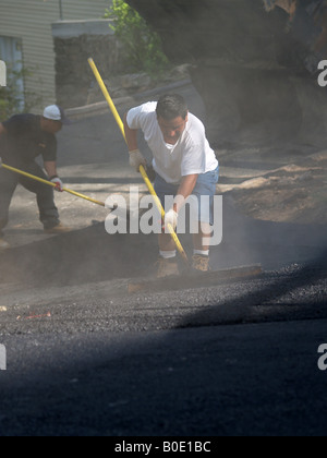 Giorno operai spargimento su asfalto appena costruito passo carraio Foto Stock