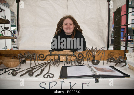Giovane donna titolare di stallo vendita di fatto a mano in ferro battuto attrezzi di uso domestico mercato Machynlleth Powys Wales UK Foto Stock