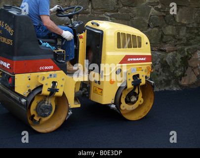 Workman panini freschi su asfalto appena costruito passo carraio Foto Stock