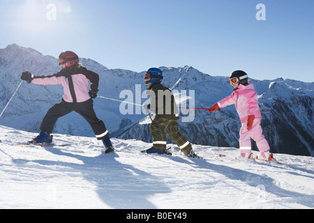 Bambini passeggiate lungo una discesa con gli sci ai piedi Foto Stock