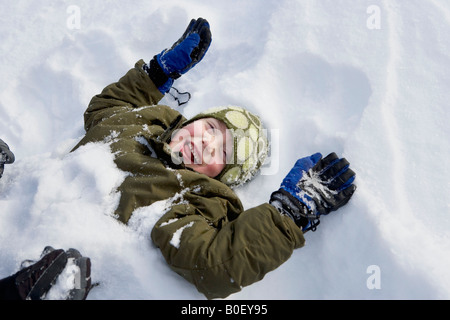 Giovane ragazzo disteso nella neve Foto Stock