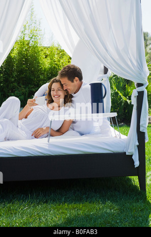 Giovane avente colazione a letto in giardino Foto Stock