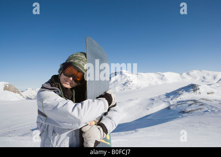 Snowboarder abbracciando snowboard Foto Stock