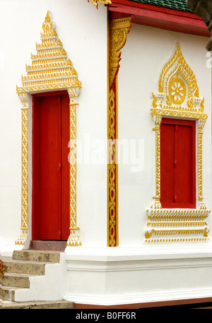 Colorata di rosso e oro porte dipinte al tempio buddista complesso di Wat Haripunchai Lampun Thailandia Foto Stock