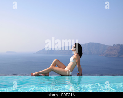 Donna seduta sul bordo di una piscina Foto Stock