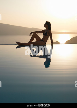 Donna seduta sul bordo di una piscina Foto Stock