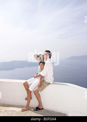 Giovane appoggiato su di un muro basso, vista mare Foto Stock