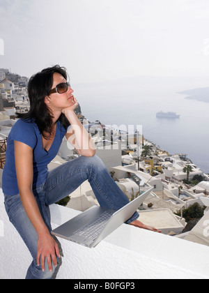 Donna con notebook seduti su un muretto Foto Stock