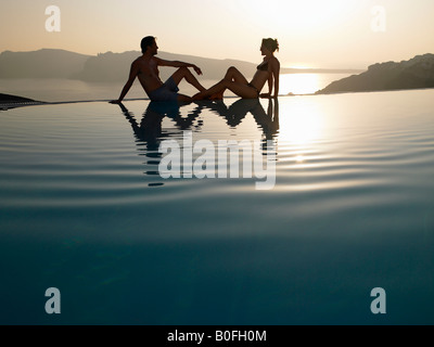 Giovane seduto sul bordo della piscina Foto Stock