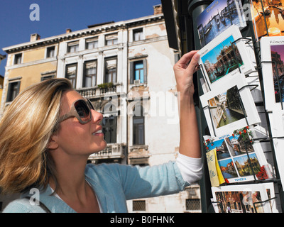 La donna la scelta di una cartolina, sorridente Foto Stock