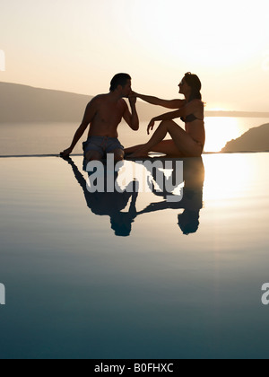 Giovane seduto sul bordo della piscina Foto Stock