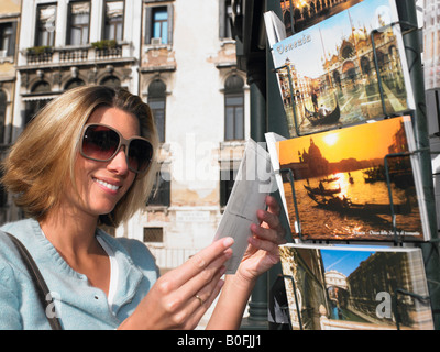 La donna la scelta di una cartolina, sorridente Foto Stock