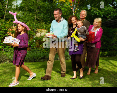 Famiglia in arrivo con torta di compleanno Foto Stock