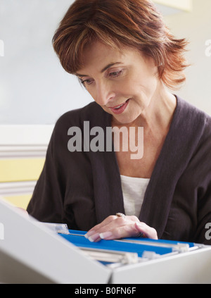 Senior donna che guarda attraverso i file Foto Stock