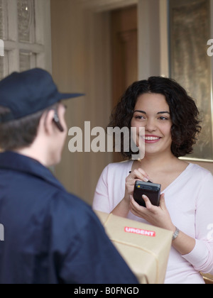 Donna firma per il pacchetto con corriere Foto Stock