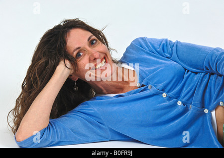 Attraente di mezza età donna caucasica con capelli lunghi marrone sdraiato sul pavimento Foto Stock