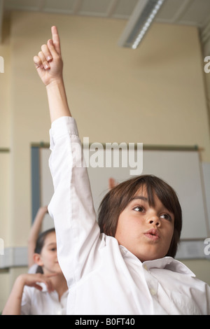 Ragazzo alzando la mano in aula Foto Stock