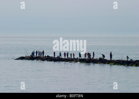 La gente alla pesca oceanica da una stretta penisola di roccia Foto Stock