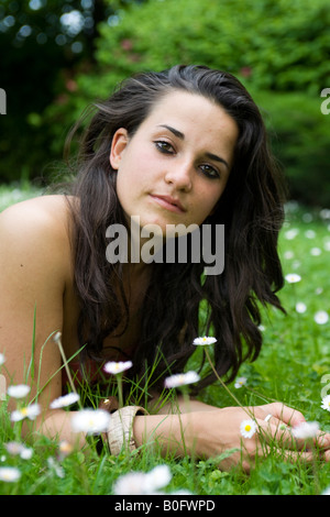 Ritratto di una giovane donna che stabilisce nel giardino tra margherite Foto Stock