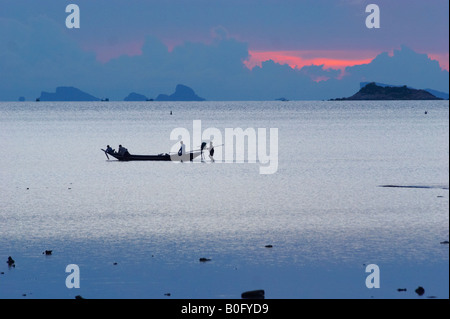 Local Thai fishernem spingendo longtail boat a sera durante la bassa marea Foto Stock