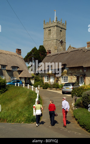 I turisti in visita a cottage con il tetto di paglia e chiesa a Godshill Isola di Wight in Inghilterra Foto Stock