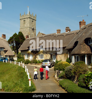 I turisti in visita a cottage con il tetto di paglia e chiesa a Godshill Isola di Wight in Inghilterra Foto Stock