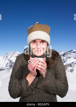 Giovane donna con drink a montagne Foto Stock