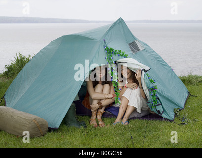 Due donne guardando fuori dalla tenda Foto Stock