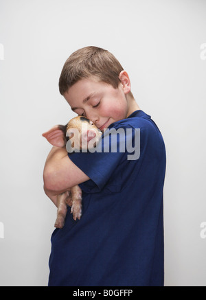 Ragazzo abbracciando maialino Foto Stock