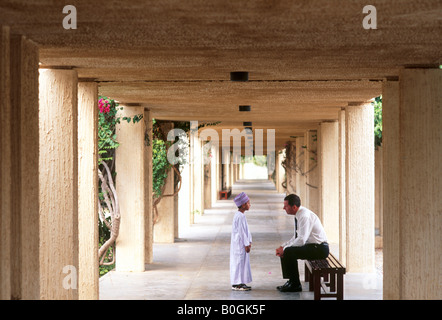 Un maestro e allievo di parlare in un corridoio all'aperto presso una scuola privata, Oman. Foto Stock