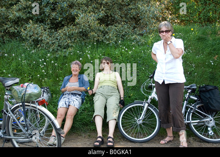 Tre donne su una bicicletta ridere per il fotografo Foto Stock
