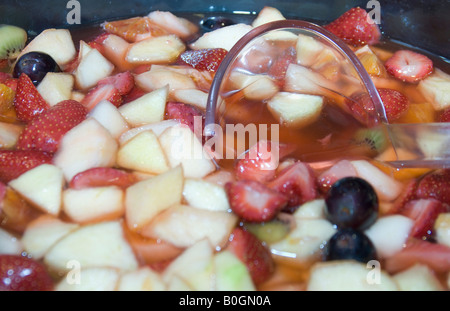 Un misto di ciotola di vetro di insalata di frutta fresca e cucchiaio da vicino Foto Stock