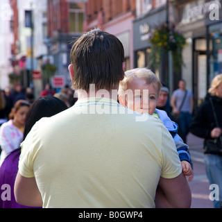 Il toddler essendo portati dal padre guardando sopra la spalla Foto Stock