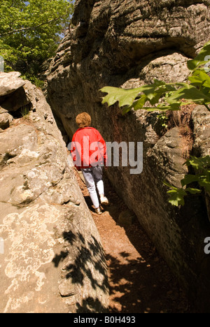 Donna caucasica (50-55) cammina attraverso Crevass fino alla grotta Rock House al Petit Jean State Park Arkansas USA Foto Stock