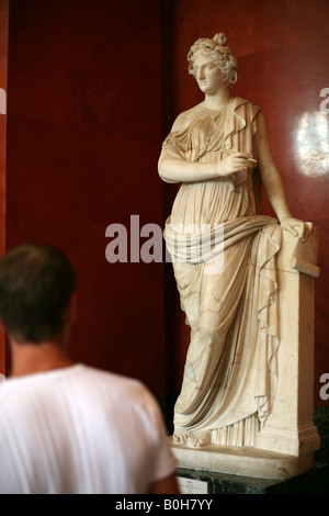 Visitatore esaminando il romano statua in marmo della Clio la musa della Storia nello Stato Museo Hermitage di San Pietroburgo, Russia Foto Stock