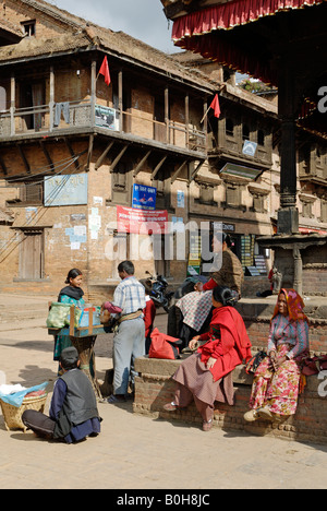 Scena di strada di gente del luogo rilassante e trading di fronte i vecchi edifici di Bhaktapur, Kathmandu, Nepal Foto Stock