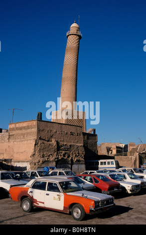 Battere vecchie auto parcheggiata di fronte la storta pendente minareto della moschea Nuriya (Jami an-Nuri, costruito 1148), Mosul, Iraq, M Foto Stock