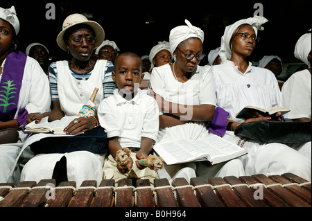 Ragazzo seduto tra canti donna giocando il marimba durante il servizio di una chiesa a Douala Camerun, Africa Foto Stock
