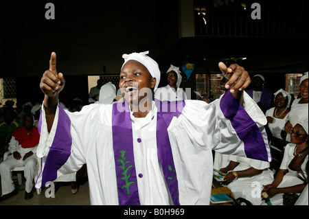 Donna vestita di bianco con anta viola in conduzione durante il servizio di una chiesa a Douala Camerun, Africa Foto Stock