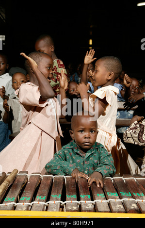 Ragazzo giovane appoggiato su una marimba davanti ai due giovani ragazze che ballano durante il servizio di una chiesa a Douala Camerun, Africa Foto Stock