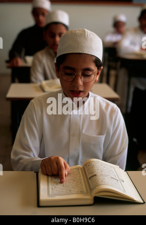 Un ragazzo lettura ad alta voce in una lezione scolastica, Arabia Saudita. Foto Stock