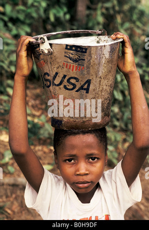 Un bambino la raccolta di acqua utilizzando un cucchiaio di olio vegetale donato da USAid, Kenema, in Sierra Leone. Foto Stock