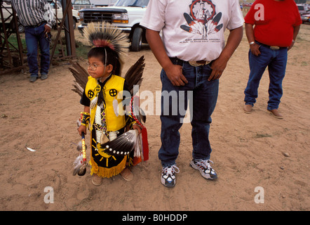 Un bambino nel tradizionale costume Navajo si erge tra uomini Navajo, STATI UNITI D'AMERICA. Foto Stock