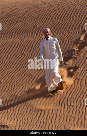 Bedouin salendo verso il basso di una duna di sabbia, ondulazioni, ridere, Wadi Rum, Giordania, Medio Oriente Foto Stock