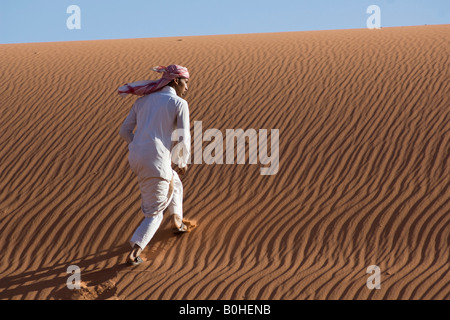 Bedouin scalare una duna di sabbia, ondulazioni, Wadi Rum, Giordania, Medio Oriente Foto Stock