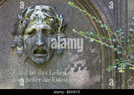 Faccia di pietra con accorata espressione sulla tomba di Giulio urbana, 1825-1879, compositore, Alter Suedfriedhof, vecchio cimitero a Monaco di Baviera Foto Stock