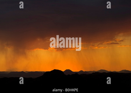 Il tramonto e la pioggia nuvole formando nel corso del Damaraland e Kaokoveld, Namibia, Africa Foto Stock