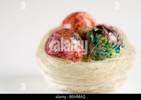 Tre colorate, dipinto di uova di Pasqua in un nido Foto Stock