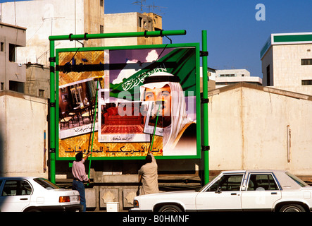 Gli uomini mettendo su un cartello pubblicitario, Arabia Saudita. Foto Stock