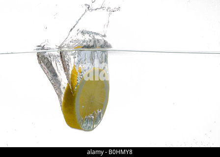 Fettina di limone cadere in acqua Foto Stock